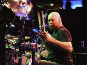 Gary Moffatt playing drums under colorful stage lights