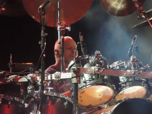 Gary Moffatt playing his drum kit under blue stage lights