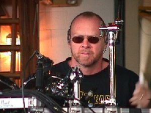 Close-up of Gary Moffatt wearing sunglasses at the drums